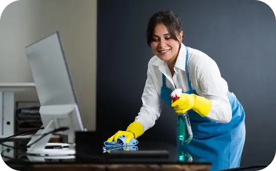 Smiling cleaner disinfecting office desk during end-of-lease cleaning service by Busy B Cleaning